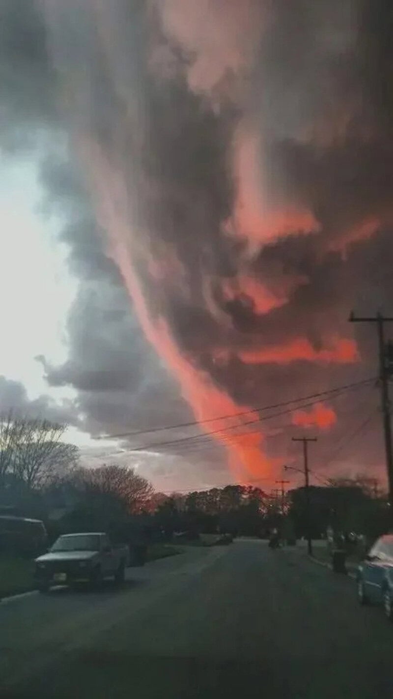 Dark stormy sky with a fiery orange cloud formation and power lines.