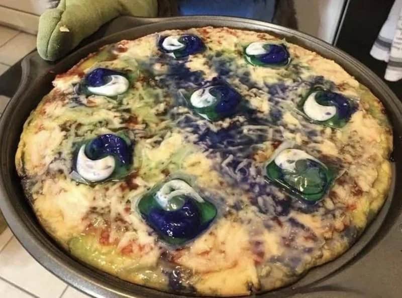Pizza with blue and green swirling toppings and eye-like decorations.