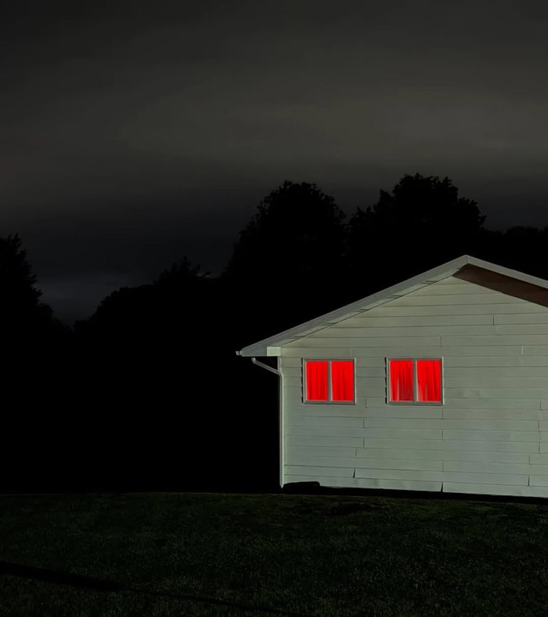 House with red curtains in a dark, cloudy night sky.