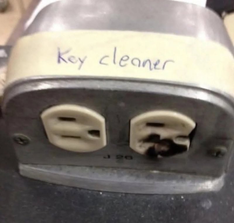 Key cleaner with a handwritten label on tape, showing a damaged electrical outlet.