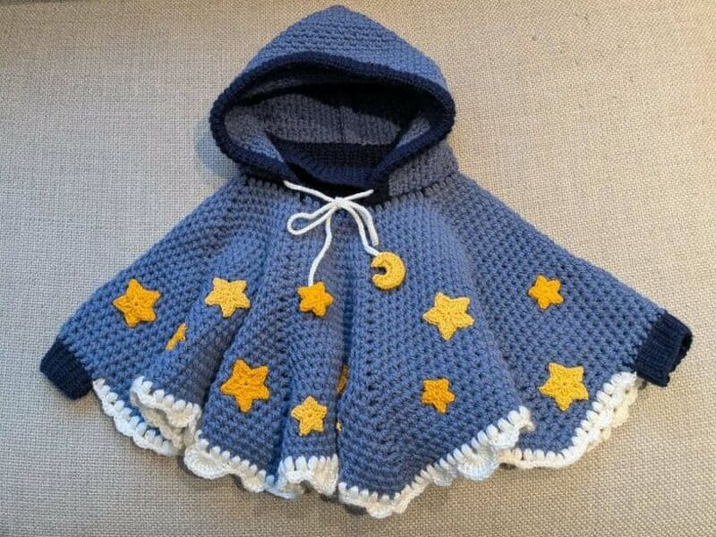 Blue crochet hooded cape with yellow stars and white trim, from crochet-amazing-designs-pictures.