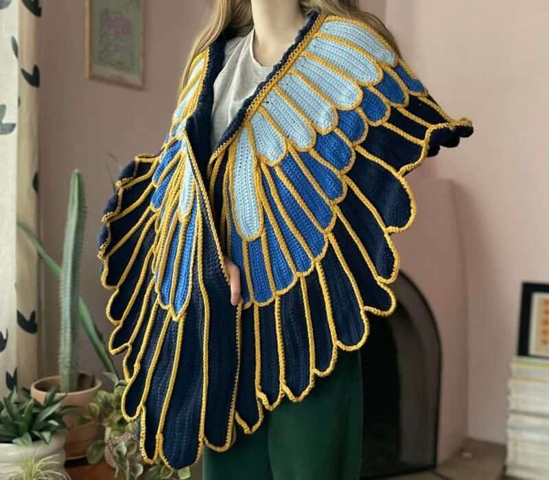 Colorful crochet shawl with blue, yellow, and light blue patterns on a person.