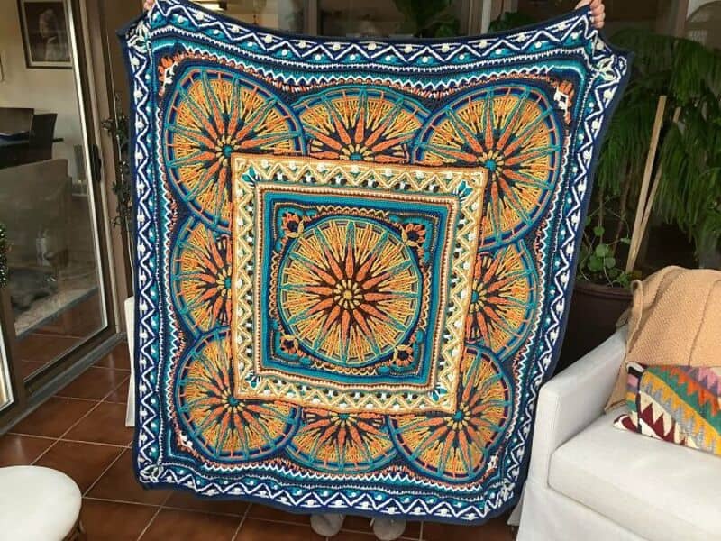 Colorful crochet blanket with geometric and circular patterns on a sofa.