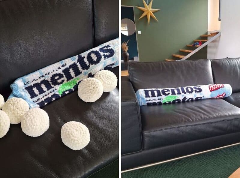 Crochet Memos pillow on black leather sofa with white pom-poms.