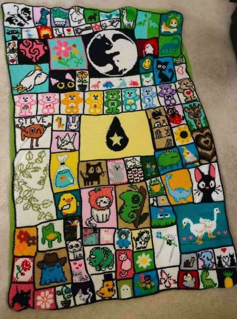 Colorful crochet blanket with various animal and character squares, including a black cat, dog, and,.