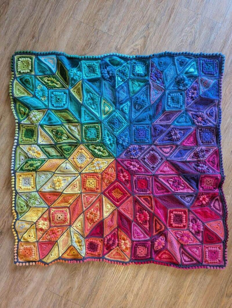 Colorful crochet blanket with geometric patterns in rainbow colors.