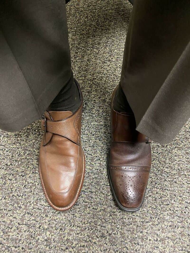 Two different colored shoes on a person's feet, one brown and one dark brown.