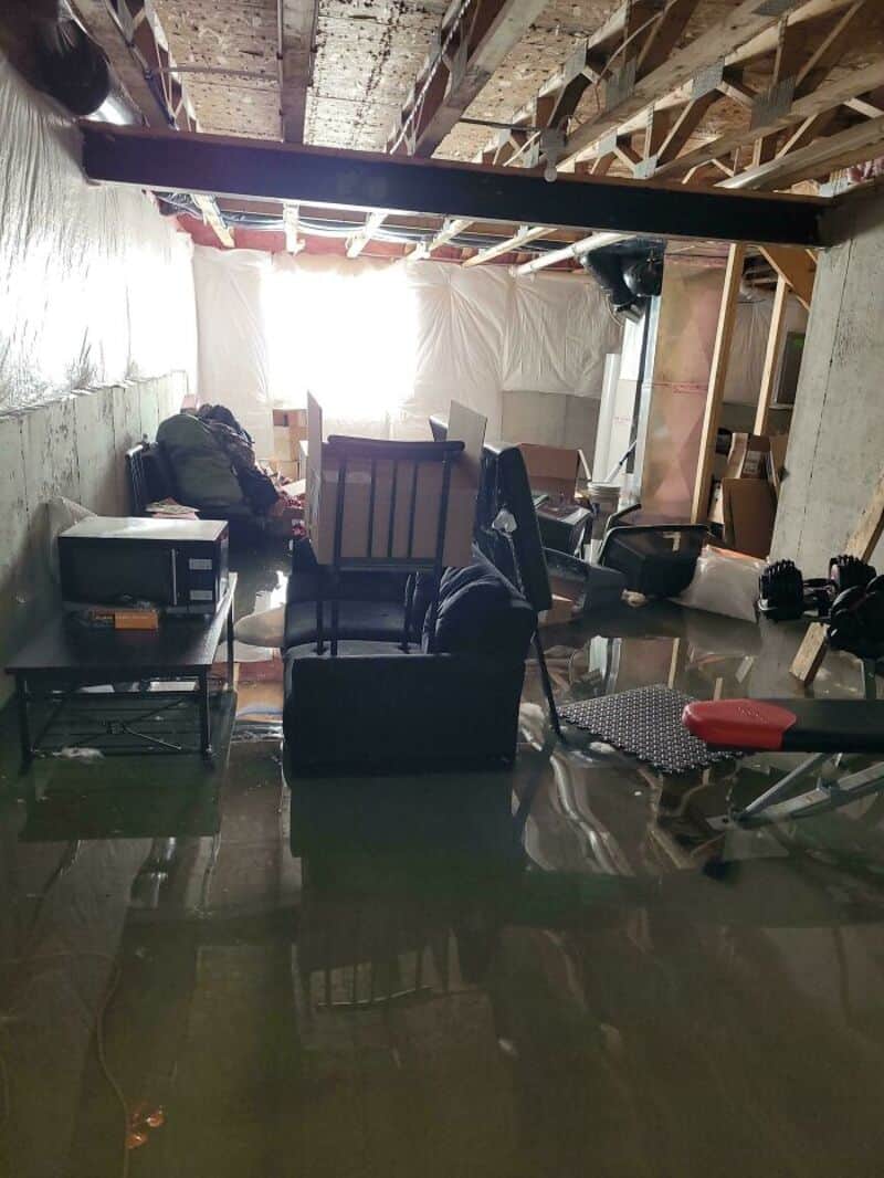 Flooded basement with furniture and equipment submerged in water.