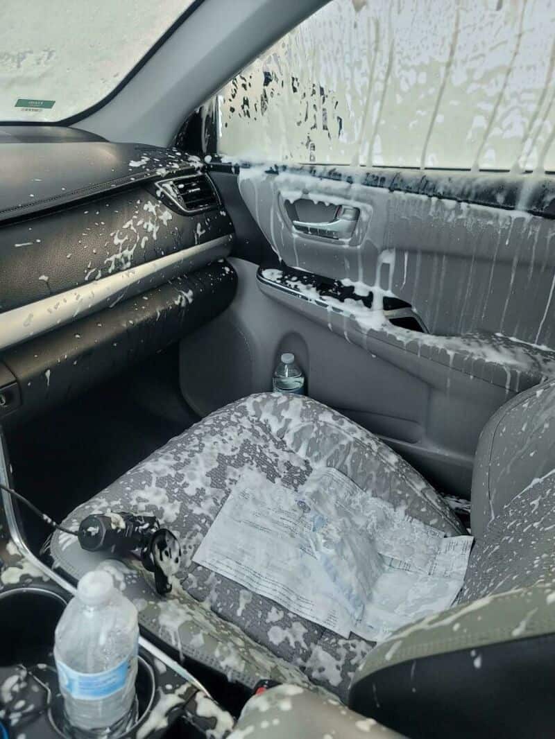 Inside a car with soapy water and foam on the dashboard, seat, and window.