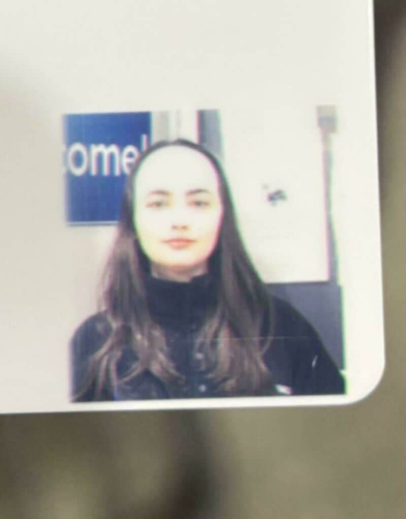 Blurry photo of a woman with long dark hair in front of a sign.