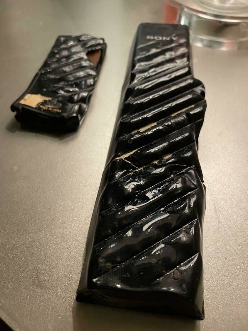 A broken black Sony remote control with a damaged cover and missing buttons.