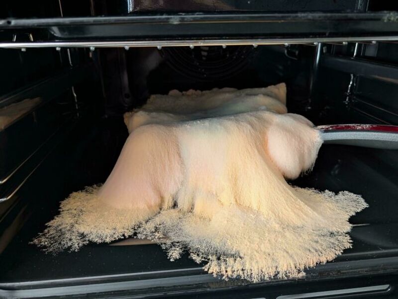 Dough spilling out of an oven onto the oven floor.