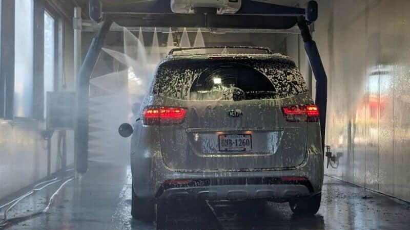 Car being washed in an automatic car wash with water and brushes.