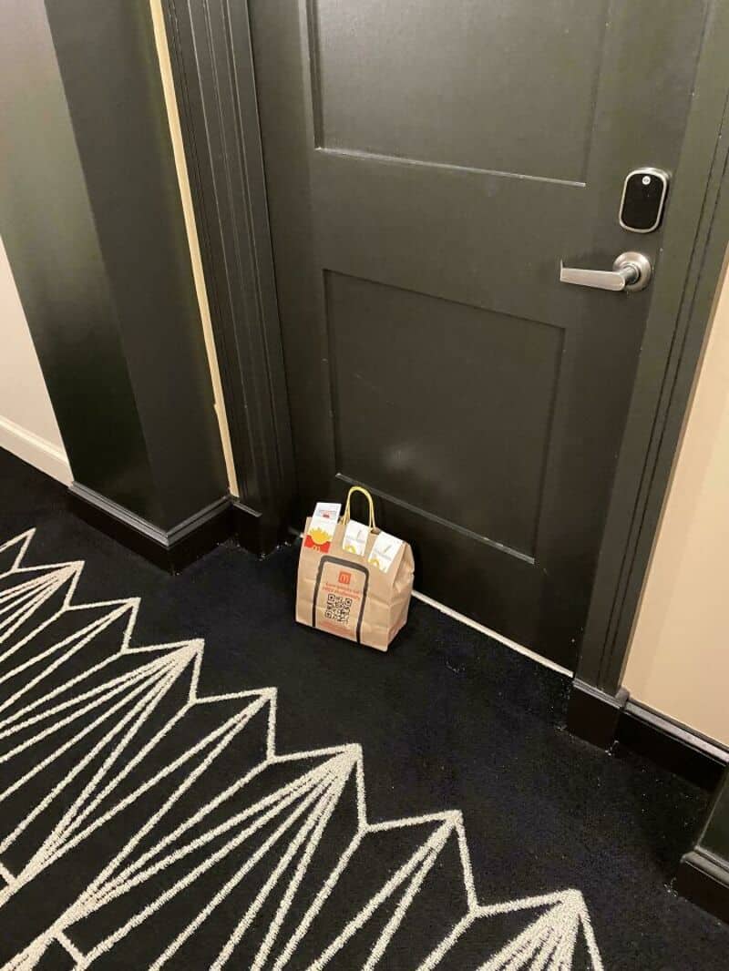 Bag of groceries on the floor in front of a door.