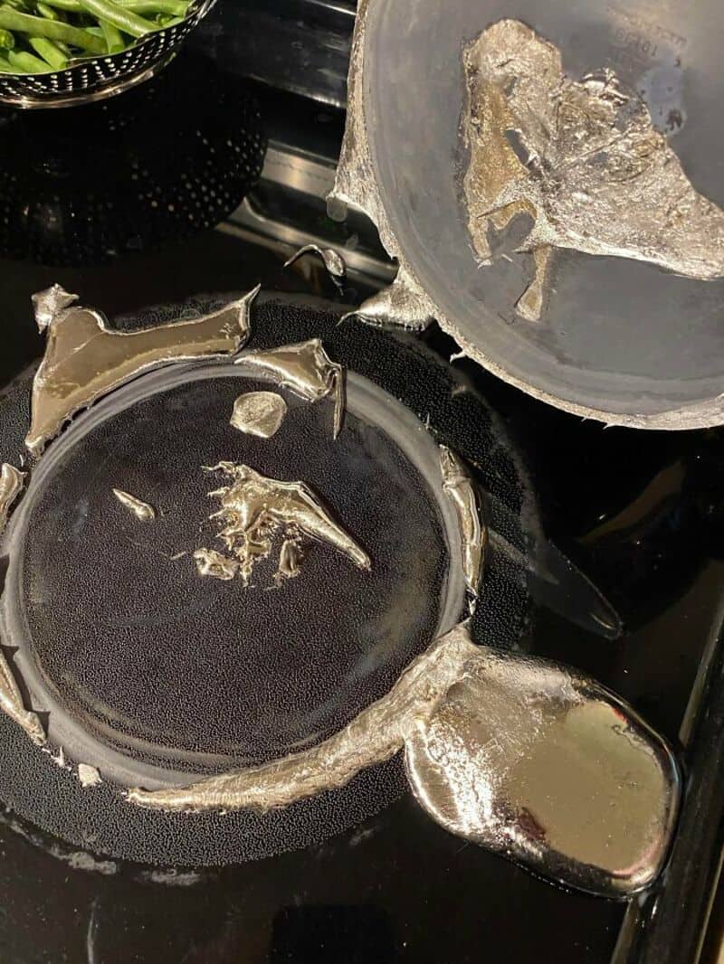 Broken and damaged metal kettle with missing parts on a stove.