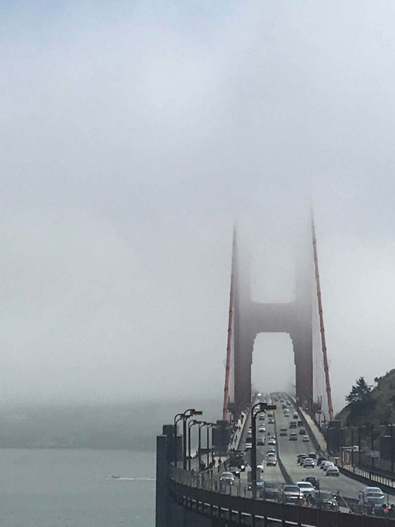 Foggy view of the Golden Gate Bridge with cars on the bridge.