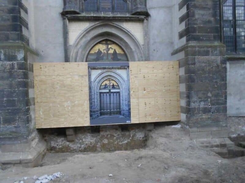 Blocked window with wooden boards on a historic building, under renovation.