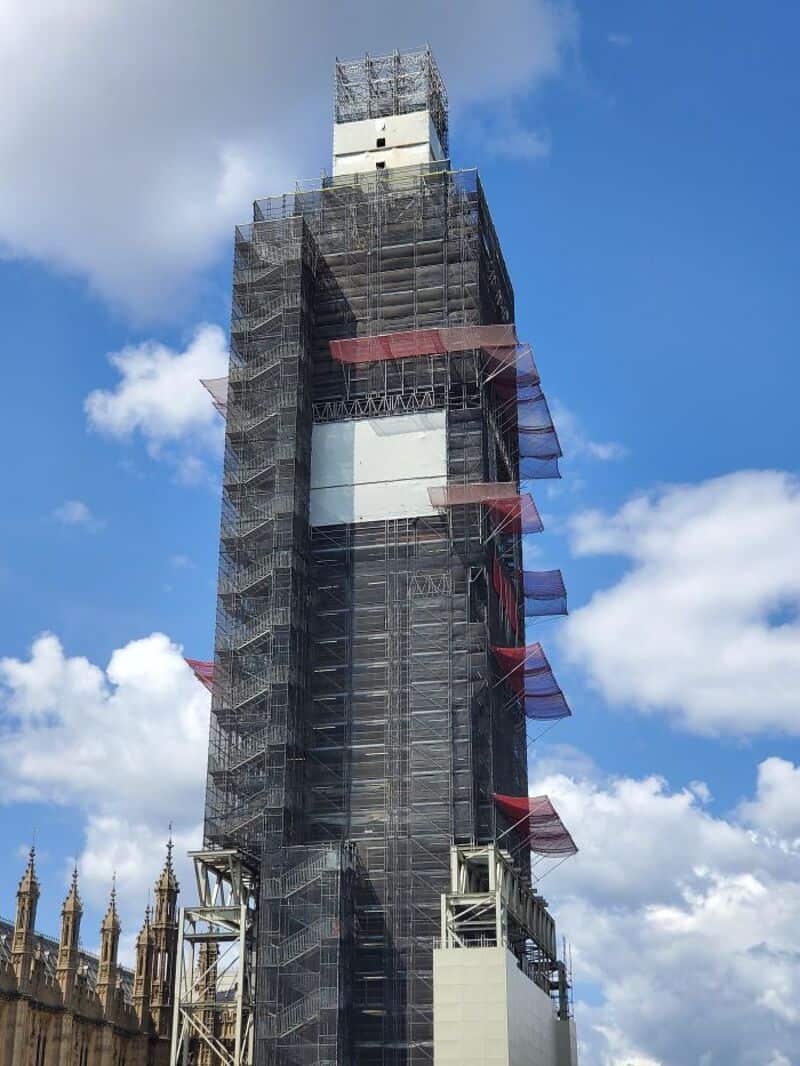 Construction site with a tall building under scaffolding and blue sky.