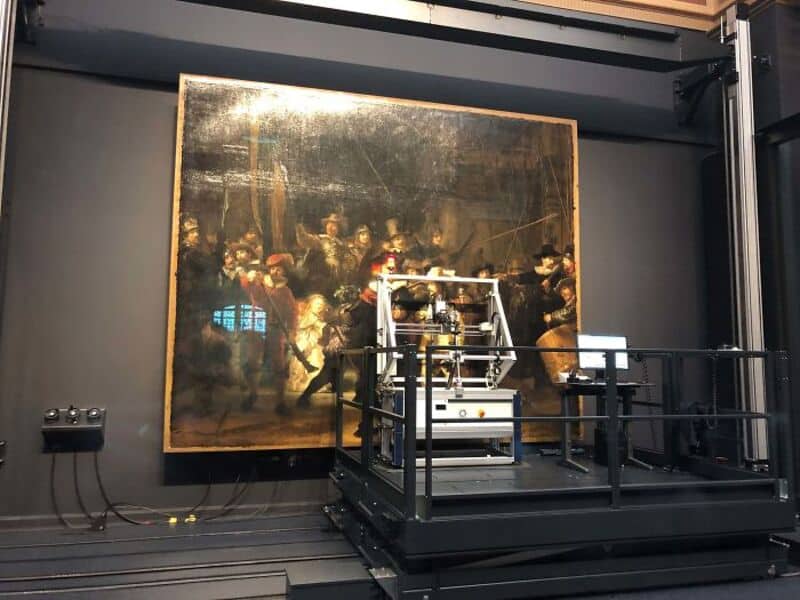 Large classical painting on wall with a robot in front of it.