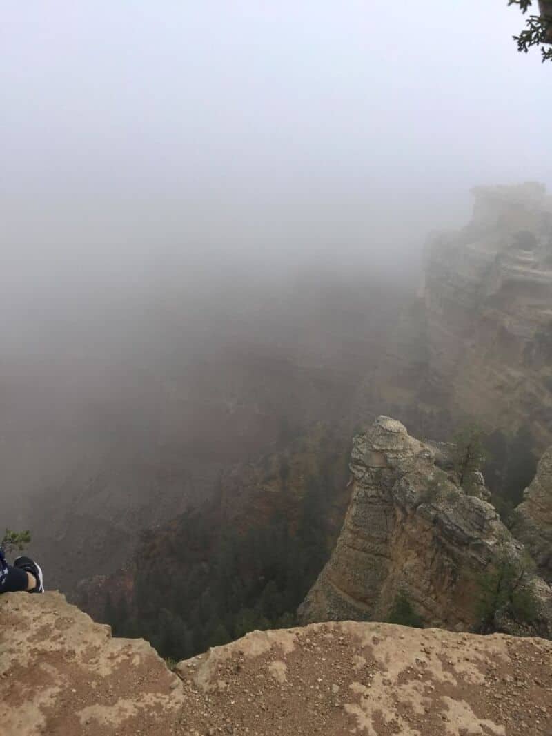 Cliff edge at the Grand Canyon shrouded in fog, obscuring the view.