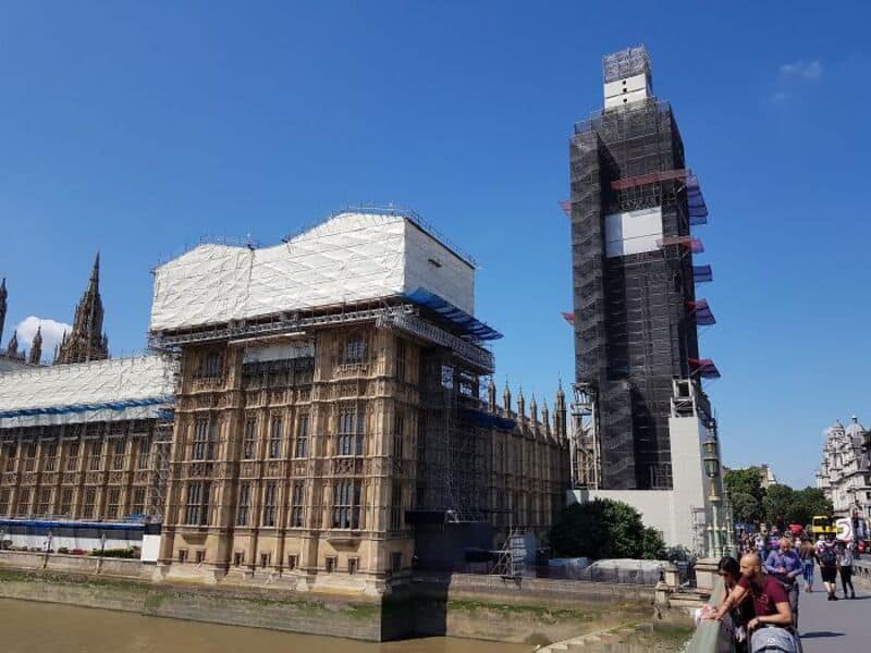 Construction site near Big Ben in London with scaffolding and workers.