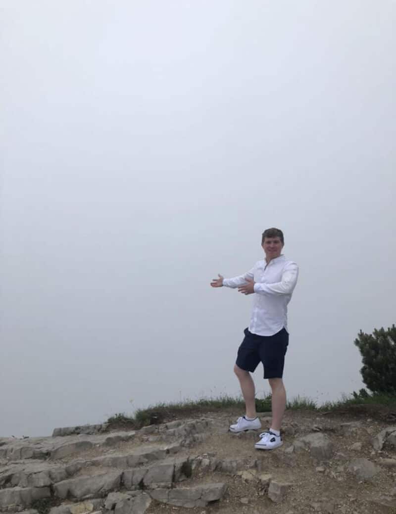 Person pointing at foggy landscape on a cloudy day.