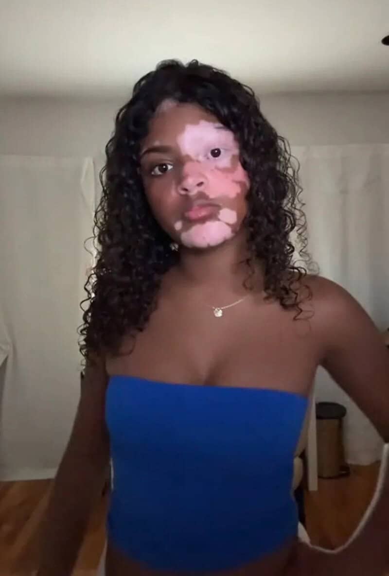 Portrait of a woman with curly hair wearing a blue strapless top.