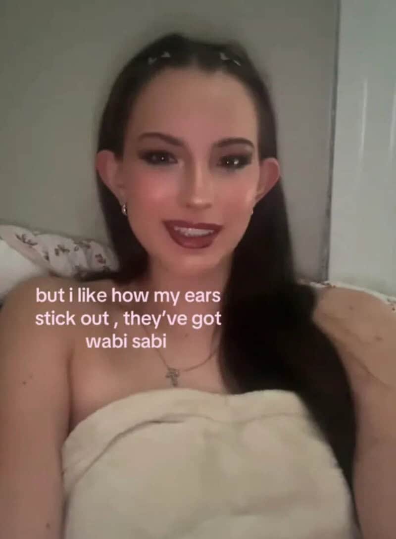 Woman with dark hair and makeup, smiling, with text about ears and wabi sabi.