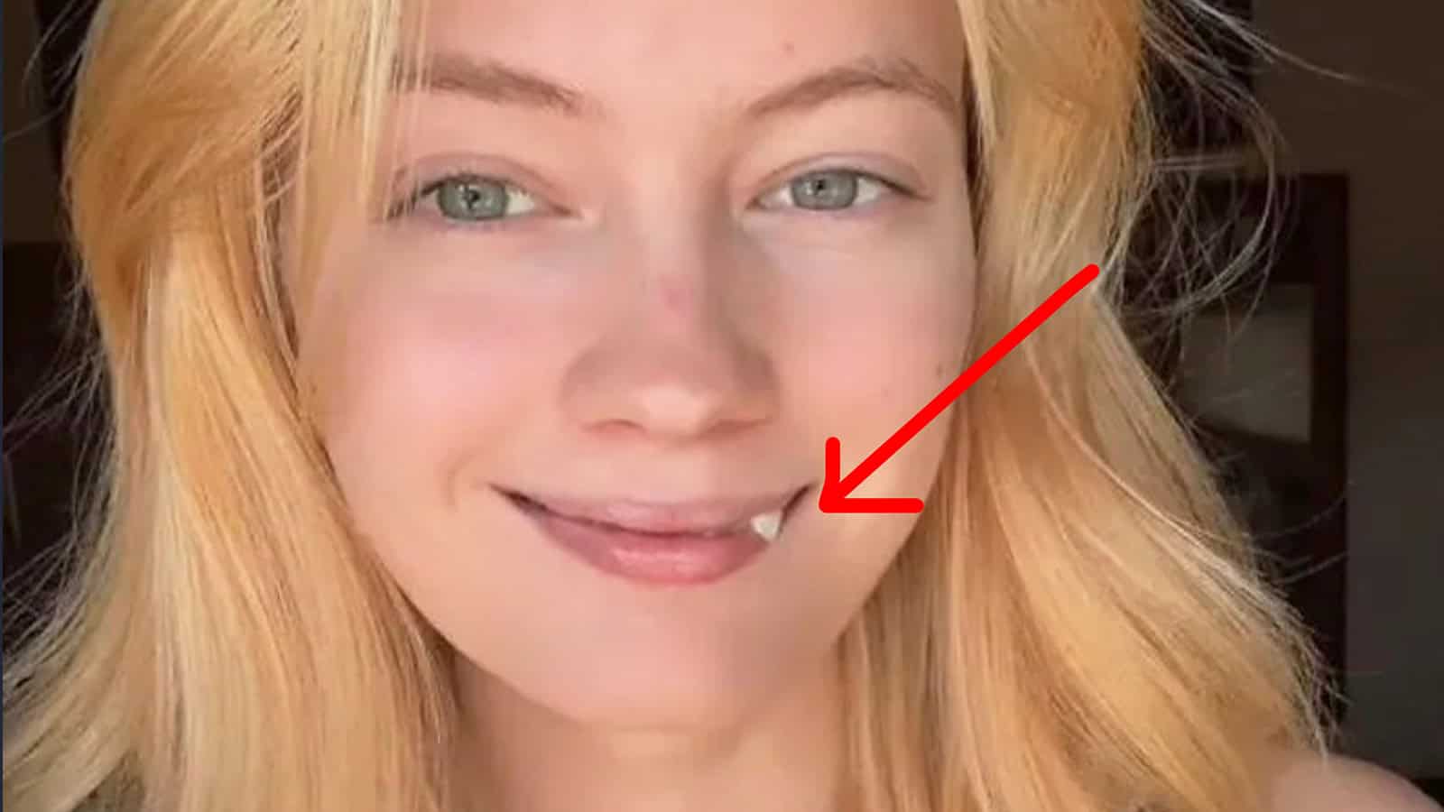 Close-up of a young woman with red hair and blue eyes smiling.
