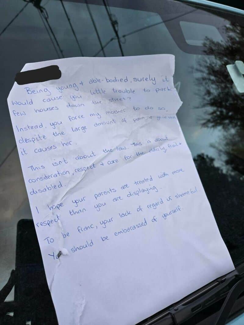 Handwritten note on paper placed on a car windshield.