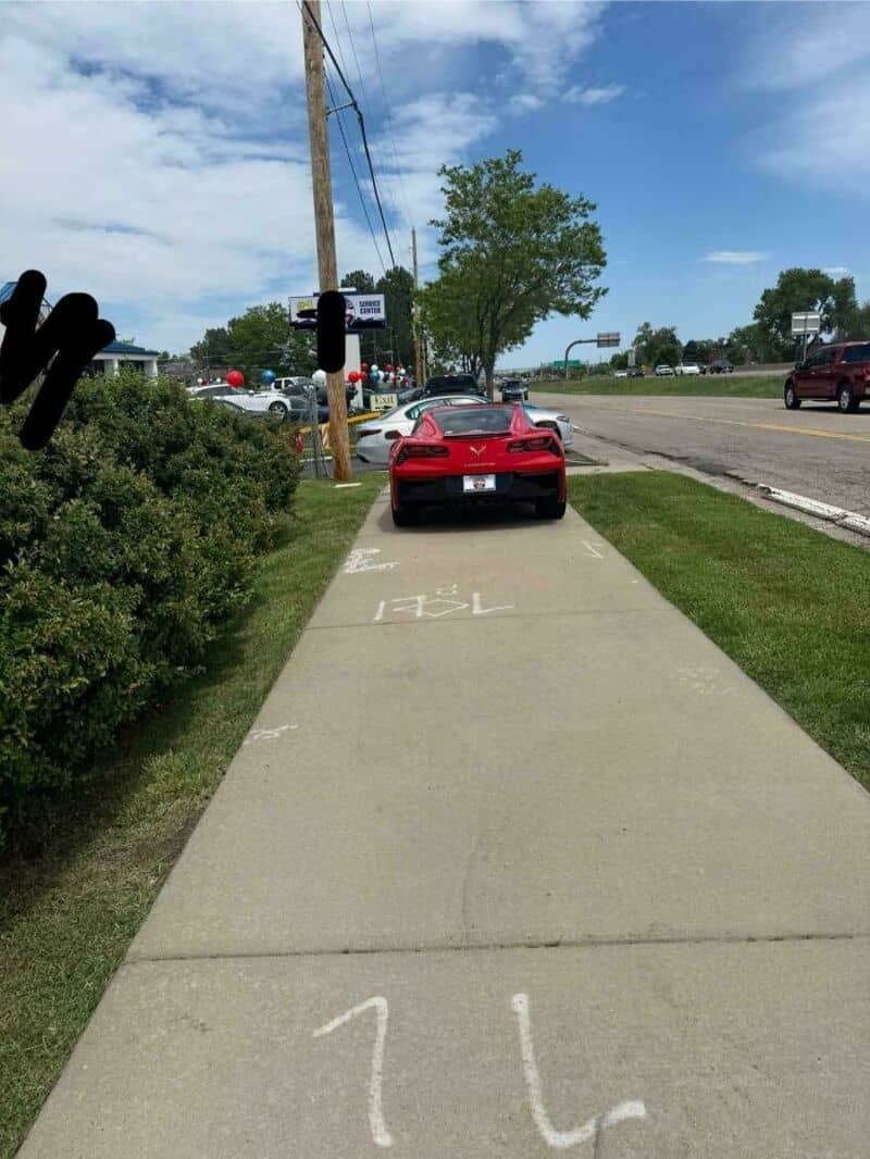 Red sports car parked on sidewalk with 'TELL' and '21' markings.