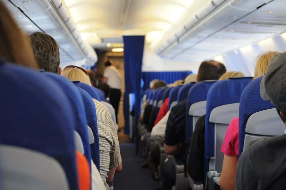 Passengers seated on an airplane, view from the back of the cabin.