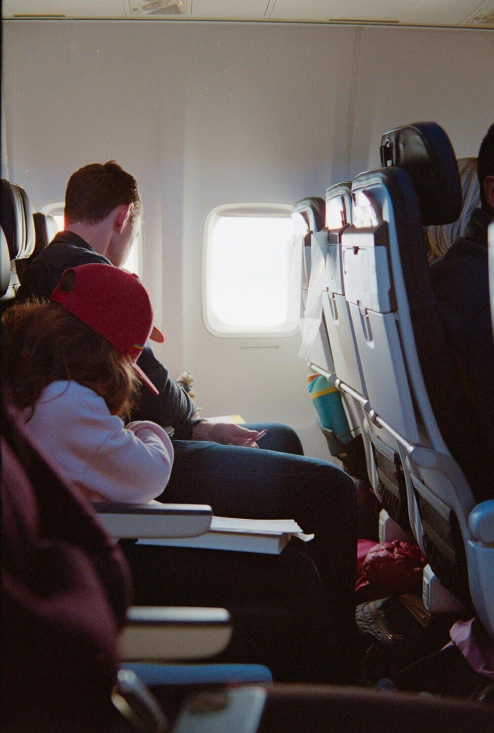 Passengers seated on an airplane, looking out the window.