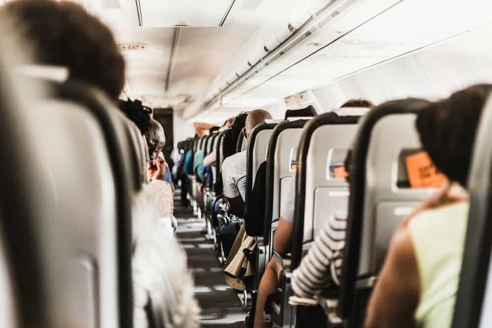 Inside view of an airplane cabin with passengers seated in rows.