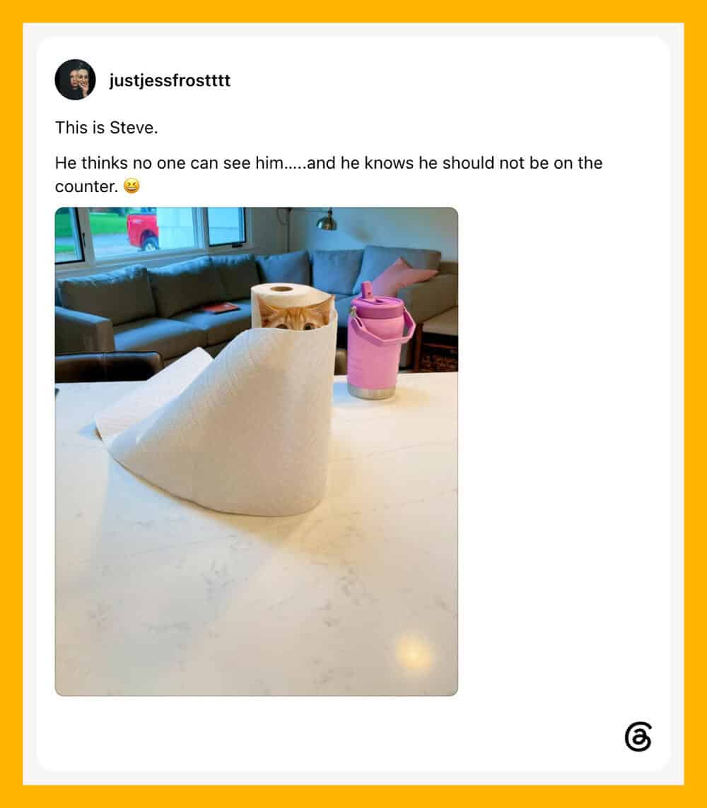 A paper cone on a table with a pink cup and a wooden container in the background.