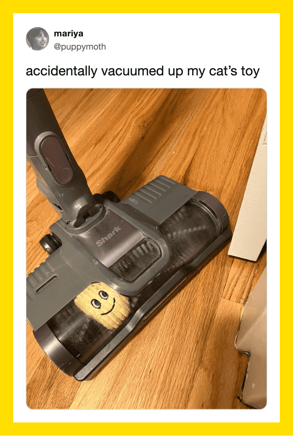 Vacuum cleaner on wooden floor with a small smiley face sticker inside.