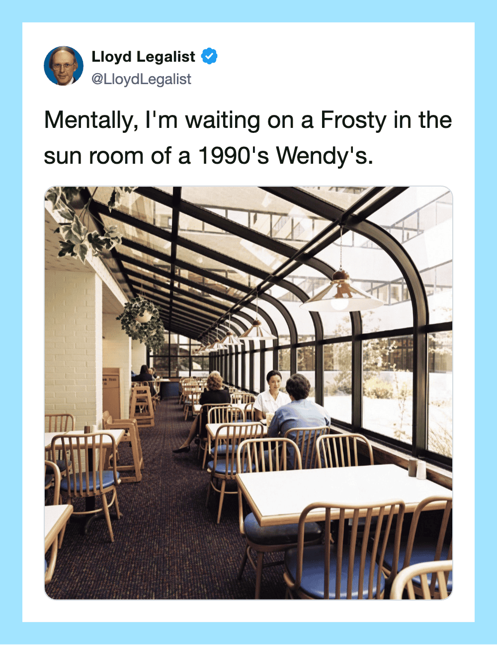 A cozy sunroom at Wendy's with wooden chairs and tables, sunlight streaming through glass ceiling.