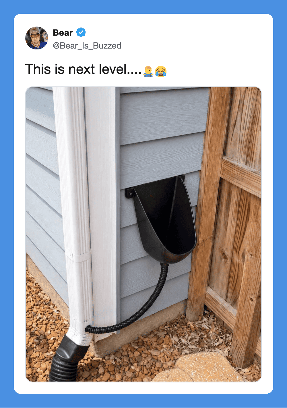 A black cat litter box attached to the house exterior with a flexible hose.