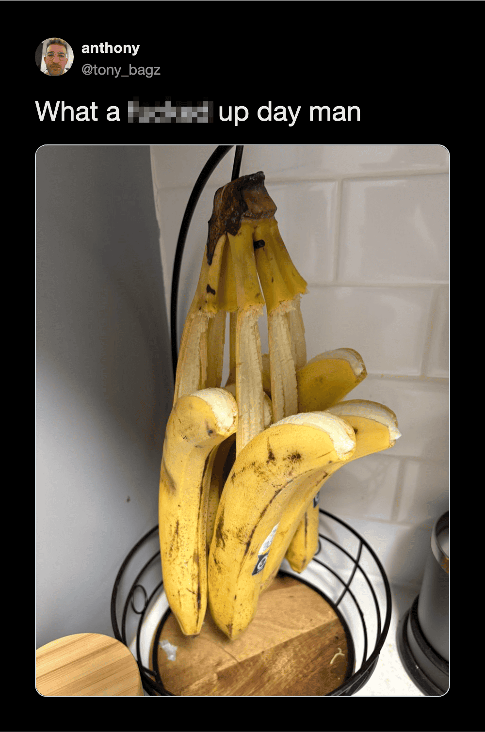 A bunch of bananas with a burnt banana on top, in a kitchen setting.