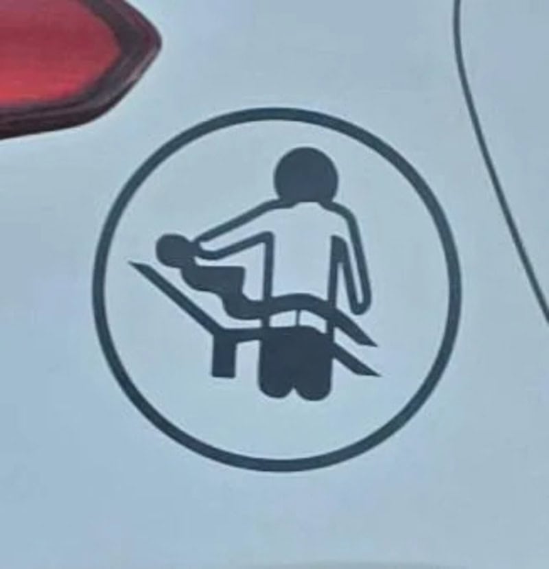 Sign showing a person with a baby in a car seat, with a red warning light above.