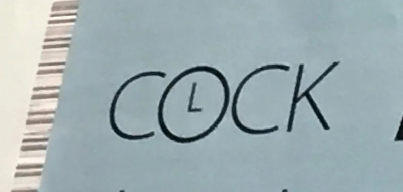 Close-up of a label with the word 'COCK' and the letter 'L' inside a circle.