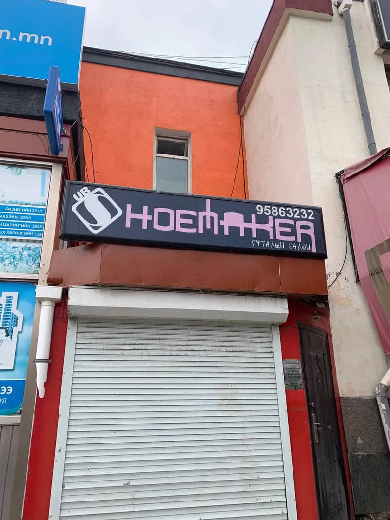 Sign for 'HOEMTHER' with a phone number, above a closed shutter door.