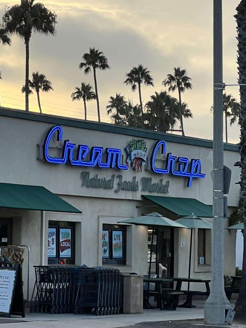 Cream Cray sign with palm trees in background at sunset.