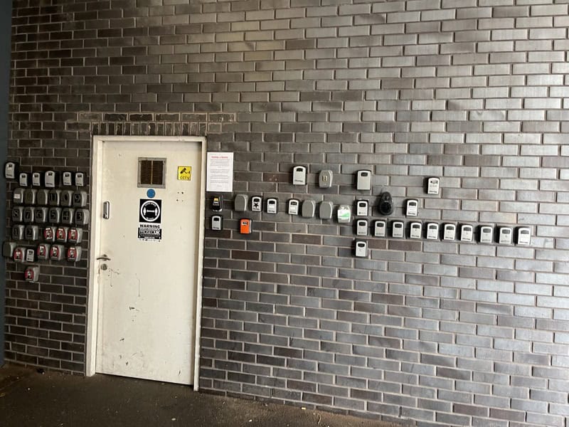 Multiple mailboxes and a door on a brick wall with a sign.