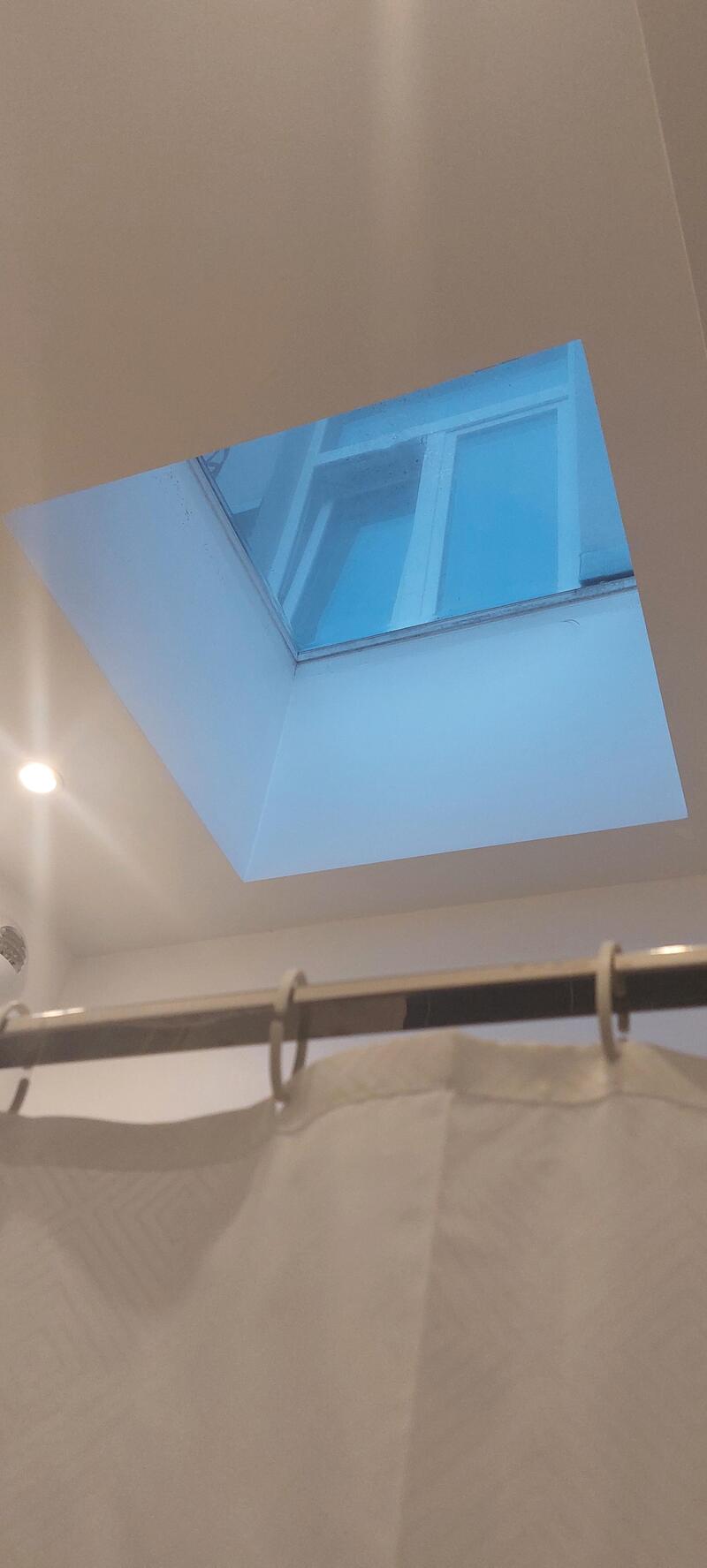 Skylight in ceiling showing blue sky and window.