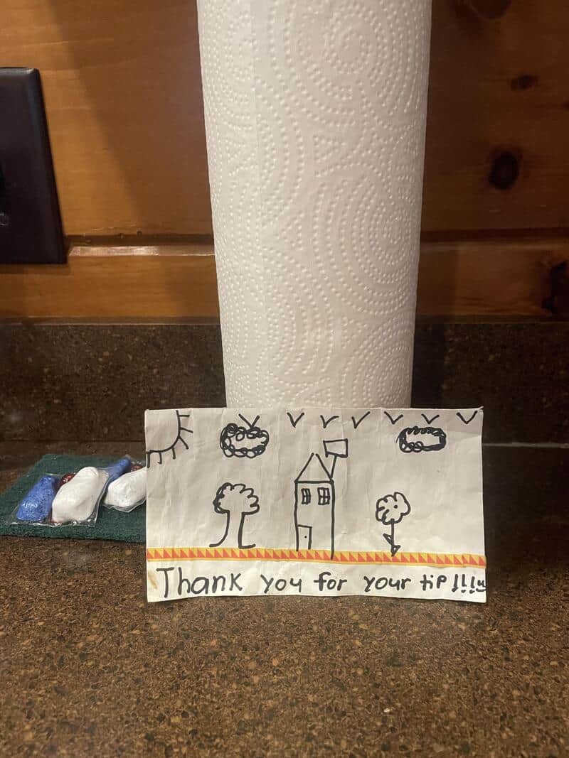Hand-drawn thank you note with trees, house, and smiley faces on paper.