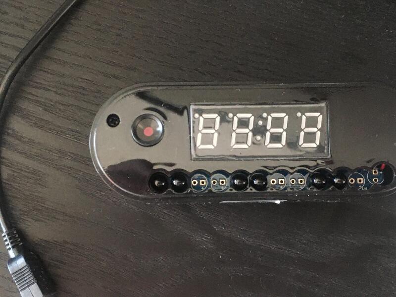 Digital clock with multiple switches below, on a dark surface.