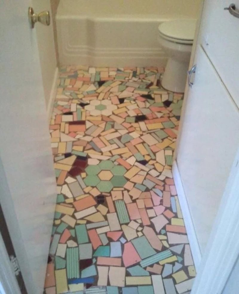 Colorful mosaic bathroom floor with a toilet and white cabinet.