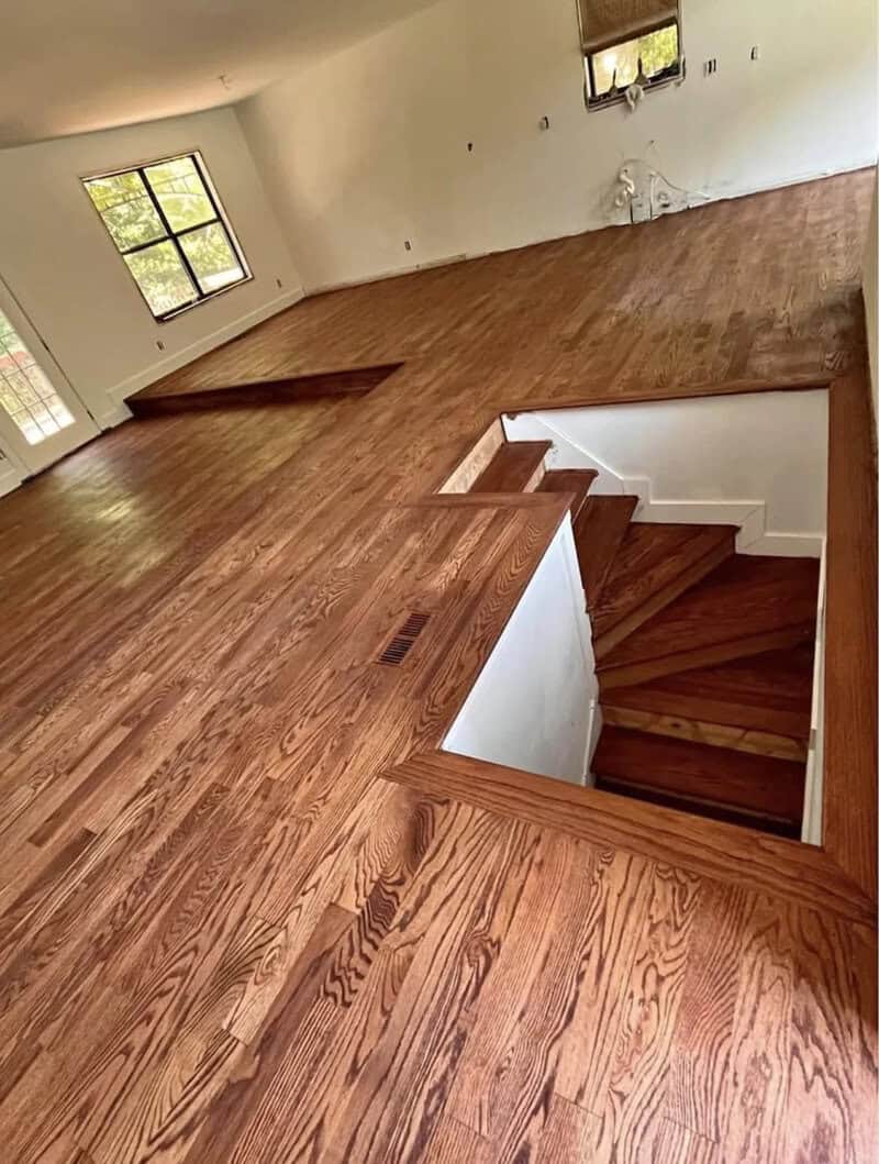 Empty room with wooden floors and stairs leading down.