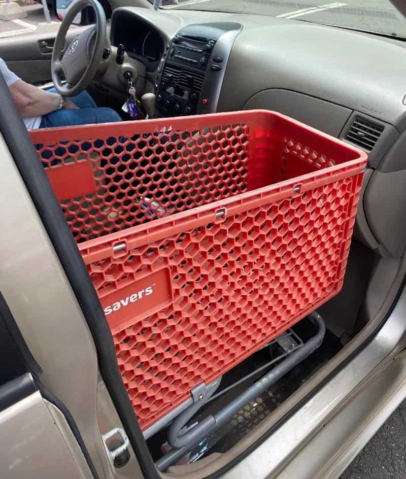 Large red shopping cart inside a vehicle, blocking the front passenger seat.